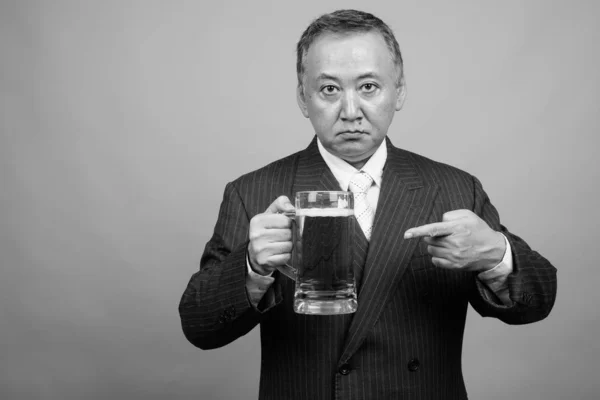Yetişkin Asyalı Adamının Gri Arka Planda Siyah Beyaz Bira Bardağını — Stok fotoğraf