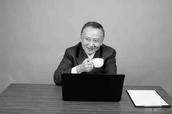 Studio Shot Mature Asian Businessman Sitting Wooden Table Gray Background — Stock Photo, Image