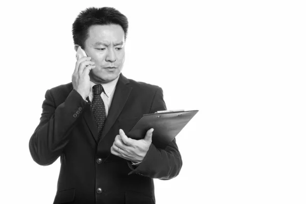 Japonais homme d'affaires lecture sur presse-papiers et parler sur téléphone mobile — Photo