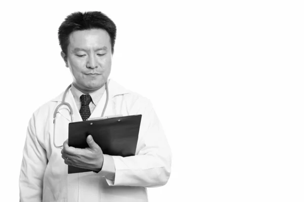 Studio shot of Japanese man doctor reading on clipboard — Stock Photo, Image