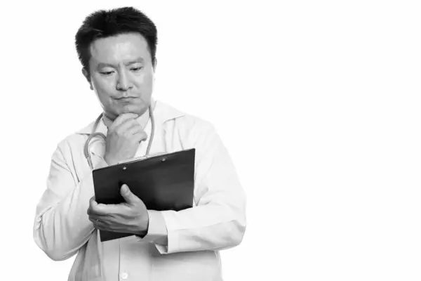 Japonés hombre médico leyendo en portapapeles mientras piensa —  Fotos de Stock