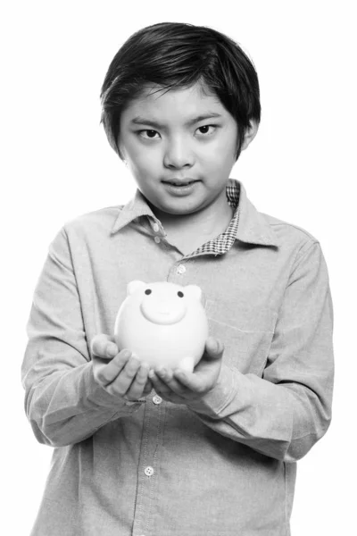 Studio shot van schattige Japanse jongen holding piggy bank — Stockfoto