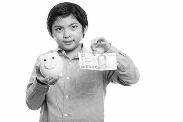 Doordachte Japanse jongen holding piggy bank en 1000 Thaise baht — Stockfoto