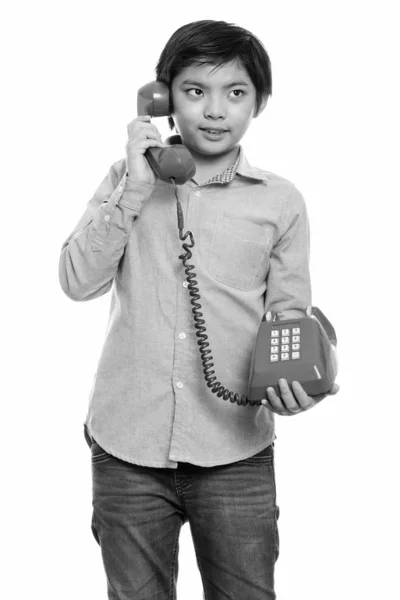 Studio shot van gelukkige Japanse jongen lachend en praten over oude telefoon — Stockfoto