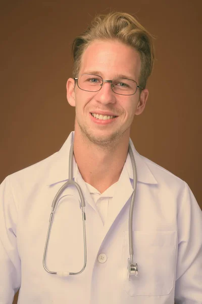 Молодий красивий чоловік лікар на коричневому фоні — стокове фото