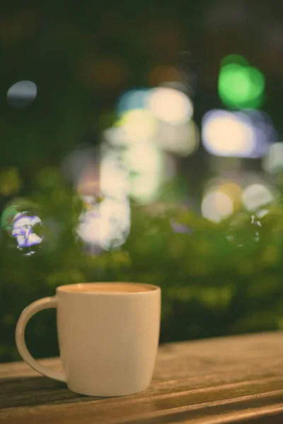 Xícara de café na mesa de madeira no restaurante à noite — Fotografia de Stock