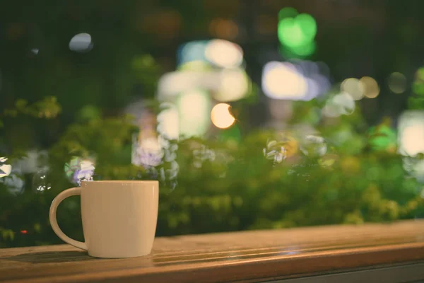 Xícara de café na mesa de madeira no restaurante à noite — Fotografia de Stock