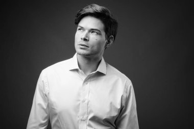 Genç ve yakışıklı iş adamının gri arka planda çekilmiş bir fotoğrafı.