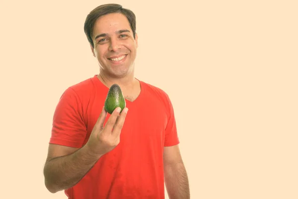 Підстрелив молодого щасливого перського чоловіка, який посміхався, тримаючи авокадо. — стокове фото