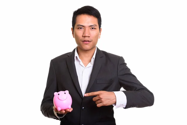 Studioaufnahme von jungen asiatischen Geschäftsmann hält Sparschwein und p — Stockfoto