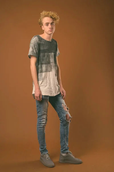 Skinny young man with curly hair against brown background — Stock Photo, Image