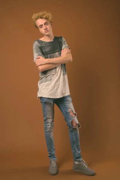 Skinny young man with curly hair against brown background — Stock Photo, Image