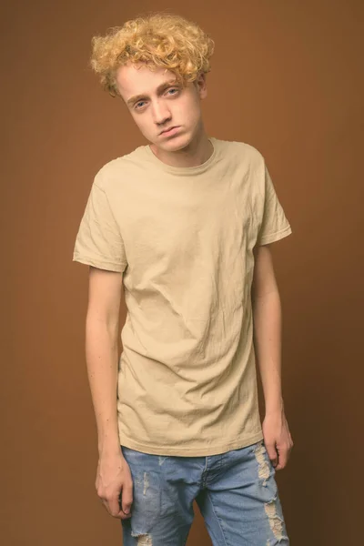 Vékony fiatalember göndör hajú, barna háttér — Stock Fotó