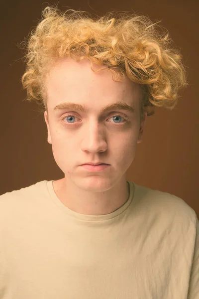 Vékony fiatalember göndör hajú, barna háttér — Stock Fotó