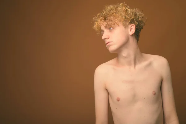Vékony fiatal férfi göndör haj félmeztelen ellen barna háttér — Stock Fotó