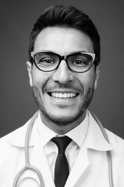 スタジオショットの若いですハンサムなヒスパニック系男性医師身に着けています眼鏡に対してグレー背景で黒と白 — ストック写真