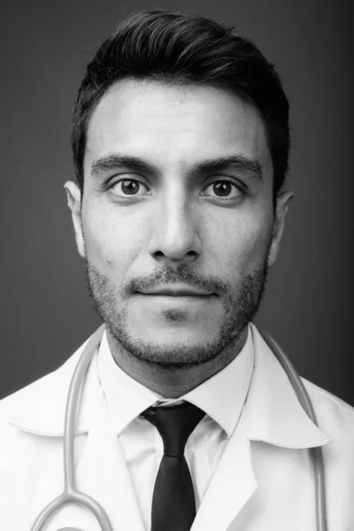 スタジオショットの若いですハンサムなヒスパニック系男性医師に対してグレー背景で黒と白 — ストック写真