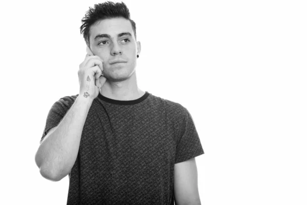 Studio shot of young man talking on mobile phone and thinking — Stock Photo, Image