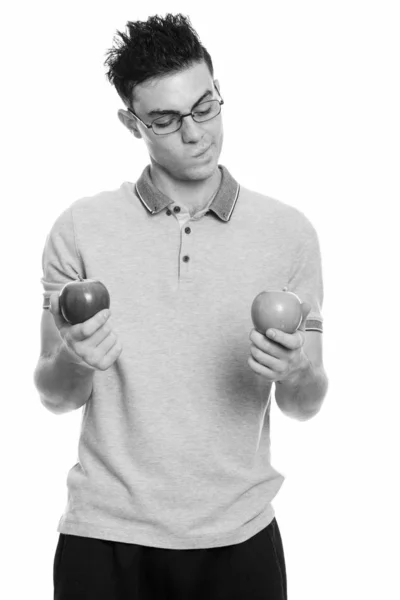 Studio shot of young man choosing between red and green apple — Stock Photo, Image