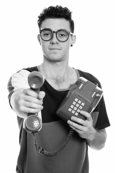 Студійний знімок молодого чоловіка, що дає старий телефон — стокове фото