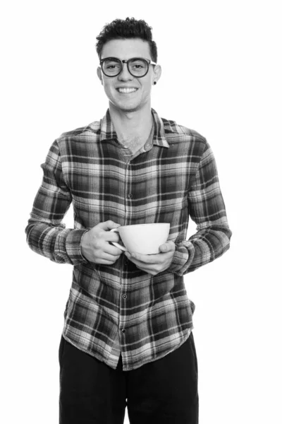 Студійний знімок щасливого молодого чоловіка, який посміхається, тримаючи чашку кави — стокове фото