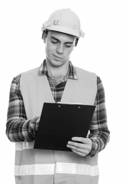 Studio shot van jonge man bouwvakker lezen op klembord — Stockfoto