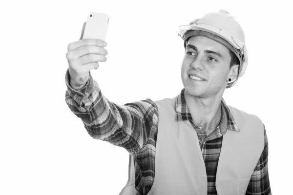 Glad ung man byggnadsarbetare ler medan du tar selfie bild med mobiltelefon — Stockfoto