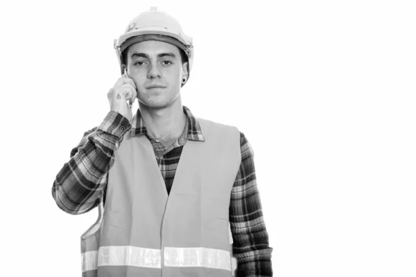 Studio bild av ung man byggarbetare talar på mobiltelefon — Stockfoto