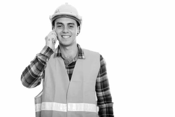 Glad ung man byggnadsarbetare ler när du talar på mobiltelefon — Stockfoto