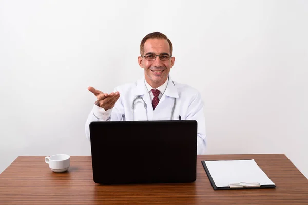 Homme persan mature médecin travaillant derrière le bureau Image En Vente