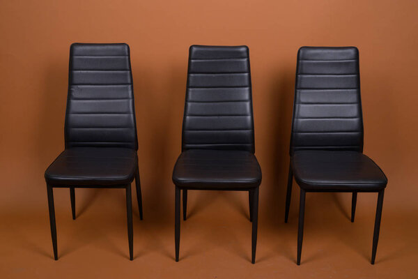 Three Leather Chairs Aligned Against Brown Background