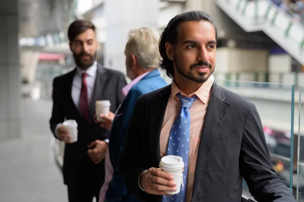 Three multi ethnic bearded businessmen together around the city