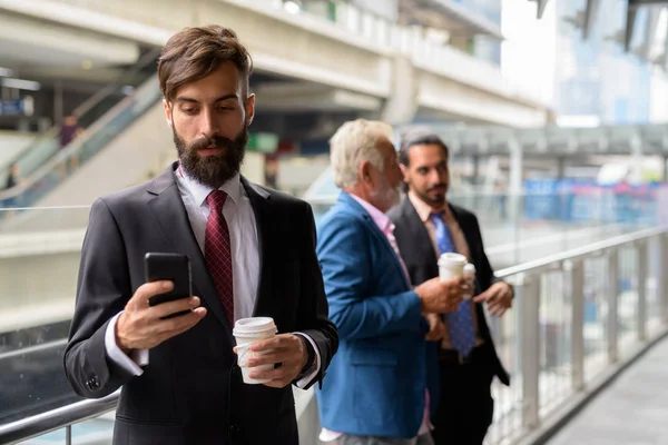 Three multi ethnic bearded businessmen together around the city