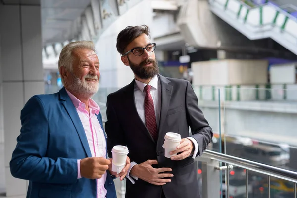 Two multi ethnic bearded businessmen together around the city