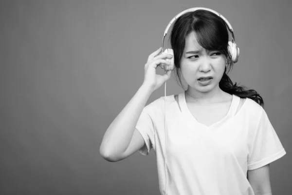 スタジオショットの若いです美しいですアジアの女性は黒と白で灰色の背景に音楽を聴く — ストック写真