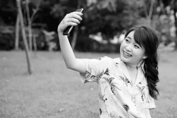 Junge schöne asiatische Touristin entspannt sich im Park — Stockfoto