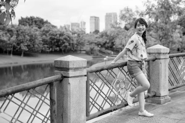 Young beautiful Asian tourist woman relaxing at the park — Stock Photo, Image