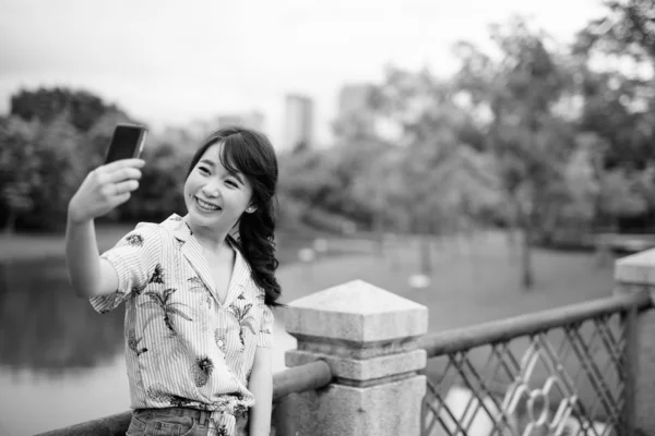 Young beautiful Asian tourist woman relaxing at the park — 스톡 사진