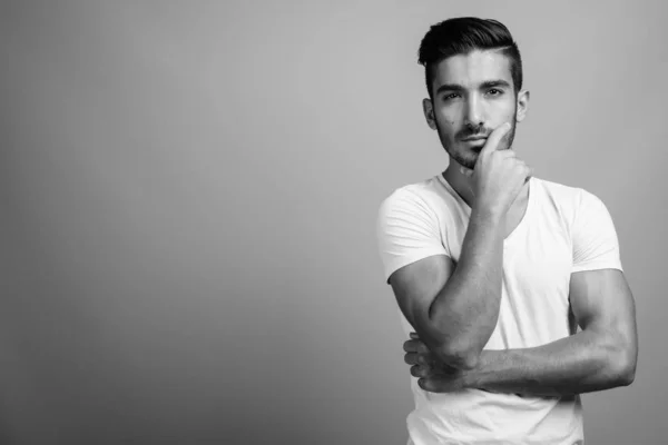 Joven hombre persa guapo contra fondo gris —  Fotos de Stock
