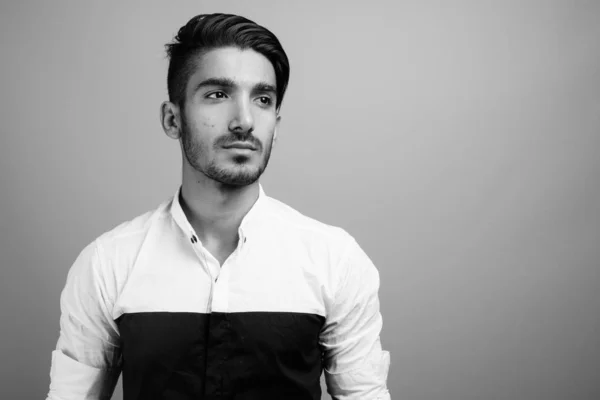 Joven hombre de negocios persa guapo contra fondo gris — Foto de Stock