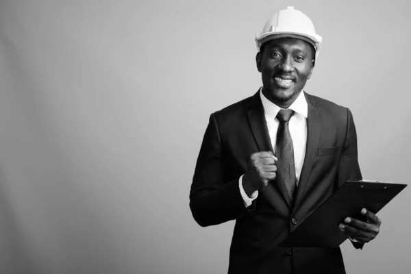 Joven hombre de negocios africano guapo con hardhat sobre fondo gris —  Fotos de Stock