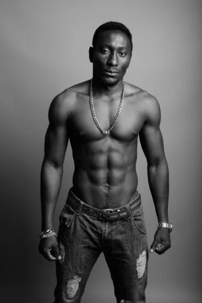 Молодой красивый африканский мужчина без рубашки на сером фоне — стоковое фото