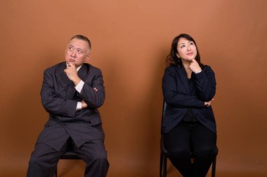 Yetişkin Japon iş adamı ve olgun Japon iş kadınının stüdyoda çekilmiş bir fotoğrafı.