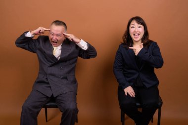 Yetişkin Japon iş adamı ve olgun Japon iş kadınının stüdyoda çekilmiş bir fotoğrafı.
