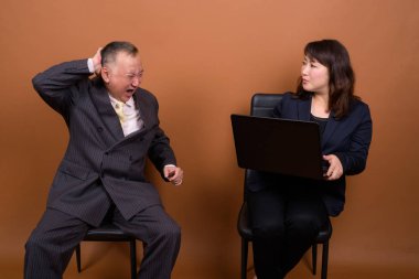 Yetişkin Japon iş adamı ve olgun Japon iş kadınının stüdyoda çekilmiş bir fotoğrafı.