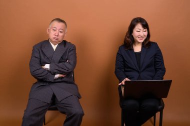 Yetişkin Japon iş adamı ve olgun Japon iş kadınının stüdyoda çekilmiş bir fotoğrafı.