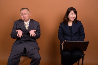 Yetişkin Japon iş adamı ve olgun Japon iş kadınının stüdyoda çekilmiş bir fotoğrafı.