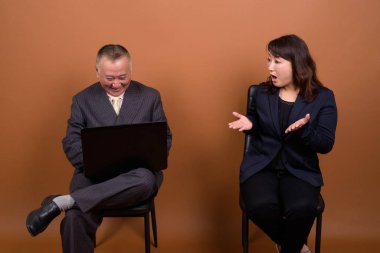 Yetişkin Japon iş adamı ve olgun Japon iş kadınının stüdyoda çekilmiş bir fotoğrafı.