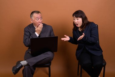 Yetişkin Japon iş adamı ve olgun Japon iş kadınının stüdyoda çekilmiş bir fotoğrafı.