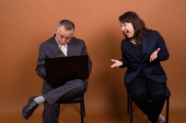 Yetişkin Japon iş adamı ve olgun Japon iş kadınının stüdyoda çekilmiş bir fotoğrafı.